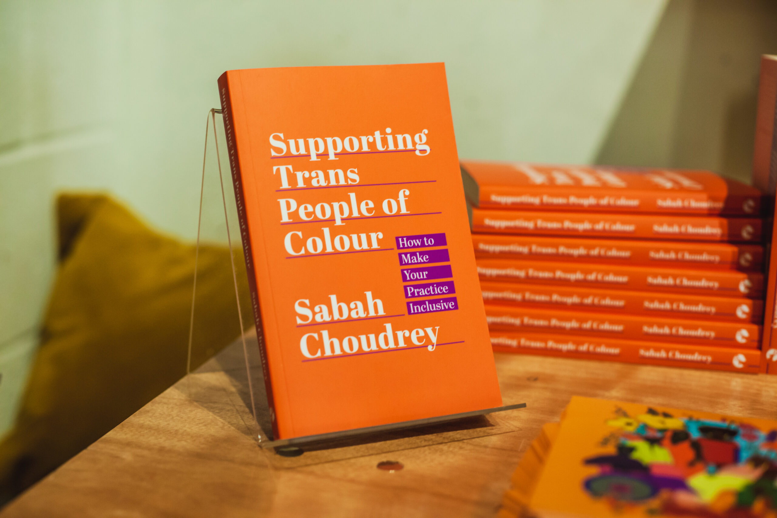 Image of 'Supporting Trans People of Colour' by Sabah Choudrey, an orange book with white text and purple accent colour